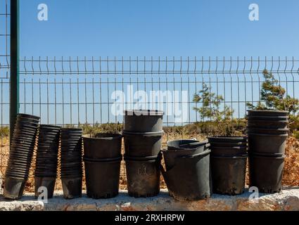 Used empty and worn-out flower pots. Background of black plastic flower pots. Stock Photo