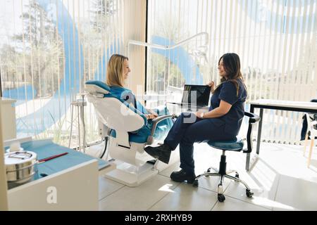 Dentist showing the result of an X-ray. General plan of the dental office with the patient and her dentist. Stock Photo