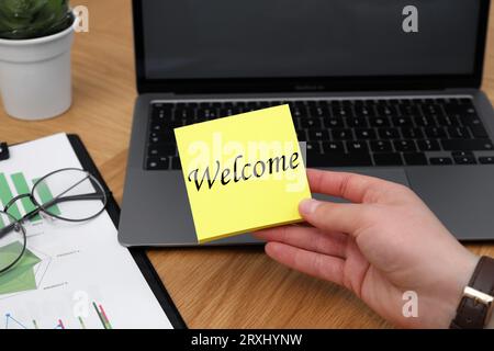 Man holding paper note with word Welcome at his office desk, closeup Stock Photo