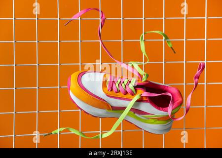 Stylish presentation of trendy sneaker on orange background Stock Photo