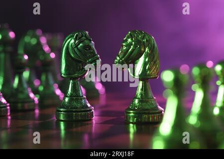 Two knights and other chess pieces on checkerboard in color light, closeup Stock Photo