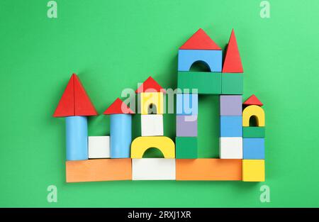 Beautiful castle of colorful blocks on green background, flat lay. Children's toy Stock Photo