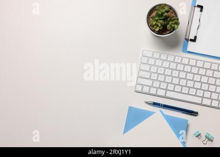 Flat lay composition with computer keyboard and different stationery on white desk, space for text. Home office Stock Photo