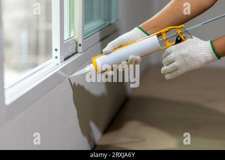 Construction worker using silicone sealant caulk the outside window frame. Stock Photo