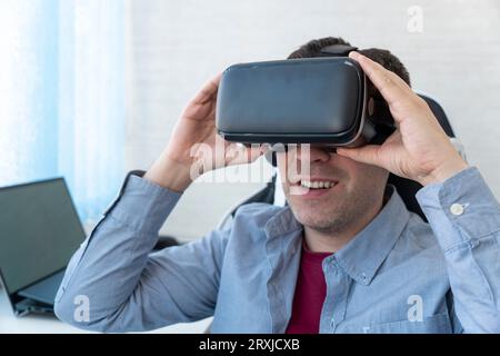 Young caucasian man using virtual reality glasses at home. People and technology metaverse concept. viewing 360 video Stock Photo