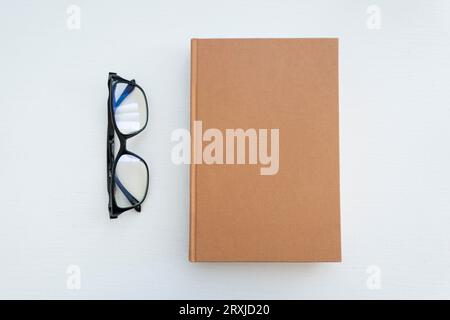 Reading glasses with books on the white table. Empty space on the cover for design and text Stock Photo