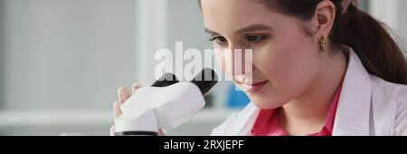 Close up of young scientist looks through microscope in laboratory. Stock Photo