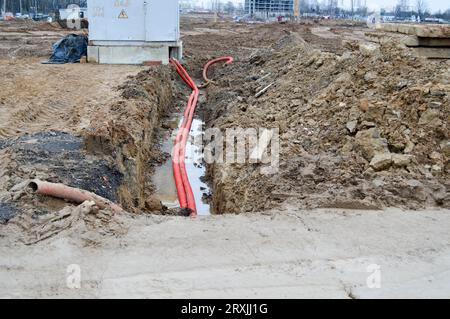 Large red plastic corrugated pipes with wires for a transformer substation at a construction site during a repair in a new underground community. Stock Photo