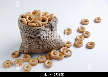 Drying or mini round bagels in sack and scattered near on white background Stock Photo