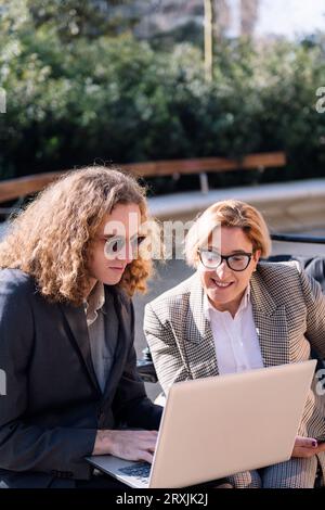 businessman and woman working outdoors with laptop Stock Photo