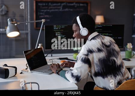 Serious programmer in wireless headphones developing new program on computer while working in IT office Stock Photo
