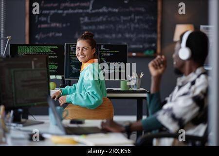 Young colleagues smiling and talking to each other during their work in IT office Stock Photo
