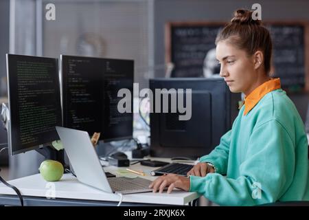 Young developer developing program on computer during her work in IT office Stock Photo
