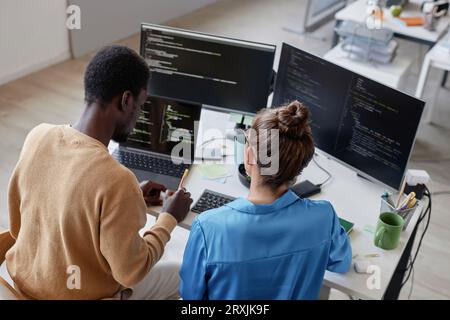 High angle view of colleagues developing security codes on computer in team during their work in IT office Stock Photo