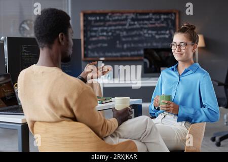 Young programmers discussing new software while drinking coffee in office Stock Photo