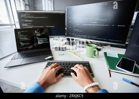 Close-up of young woman writing computer codes for program while sitting at her workplace in IT office Stock Photo