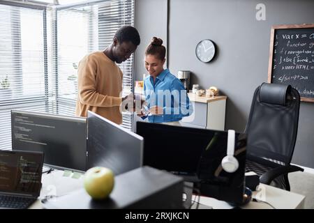 Young colleagues talking to each other during their work in IT office Stock Photo