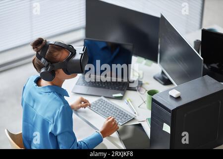 High angle view of young woman testing VR glasses in IT office Stock Photo