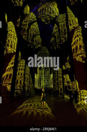 A lady views of the Nave at Canterbury Cathedral in Kent during a preview of the Luxmuralis: Renaissance, an art installation using moving light displays and original compositions to highlight the cathedral's architecture and immerse visitors in paintings and artwork from the Renaissance period during the Canterbury Festival. Picture date: Monday September 25, 2023. Stock Photo