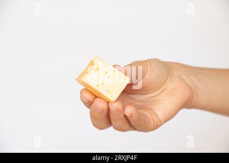 A girl holds a piece of hard cheese in her hand on a white background close-up Stock Photo