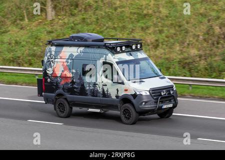 Custom Mercedes Benz Adventure Leisure motorhomes, with decals, stickers and vehicle wrapping on Mercedes-Benz Sprinter, 2500 Winnebago Revel 4×4, two-people off-roader van chassis; travelling at speed on the M6 motorway in Greater Manchester, UK Stock Photo