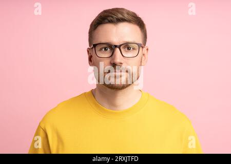 Portrait calm pensive bearded middle aged man in glasses looking at camera on pink background. Stock Photo