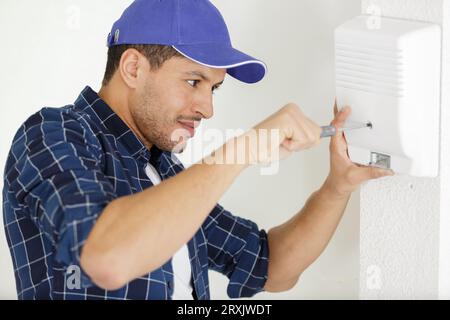 technician installing security system door sensor using screwdriver Stock Photo