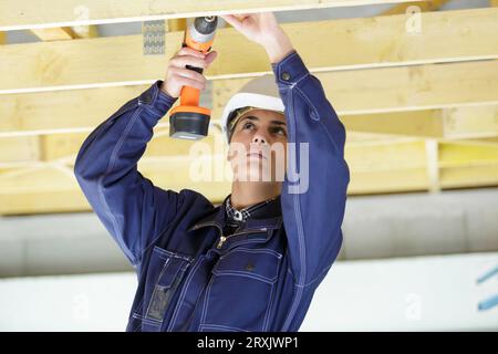 close view of female builder using cordless screwdriver overhead Stock Photo