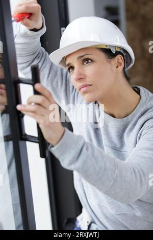 female contractor using screwdriver on patio doors Stock Photo