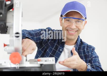 happy carpenter working on an electric buzz saw Stock Photo