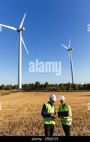 Engineers working with a laptop on a field of windmills Stock Photo