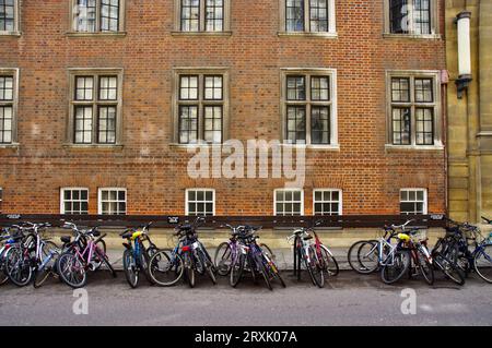 A row of Bicycles with red brick building behind. Stock Photo