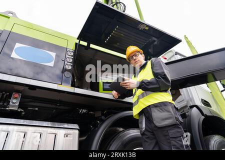 Worker with digital tablet operating construction machine equipment.. Stock Photo