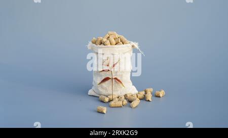 Burlap sacks or jute bag of granulated chicken feed isolated on gray background. Closeup of poultry feed or pets healthy supplement in a bag on a stud Stock Photo