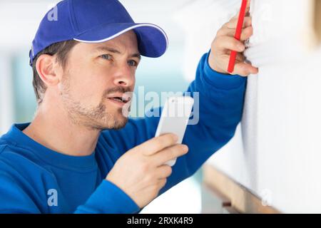 workman having conversation via the loud speaker on his smartphone Stock Photo