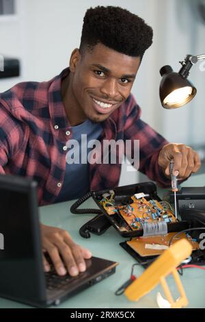 smiling man using multimeter while fixing pc Stock Photo