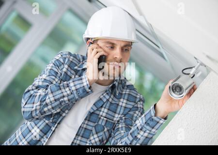 contractor checking security camera and talking on telephone Stock Photo