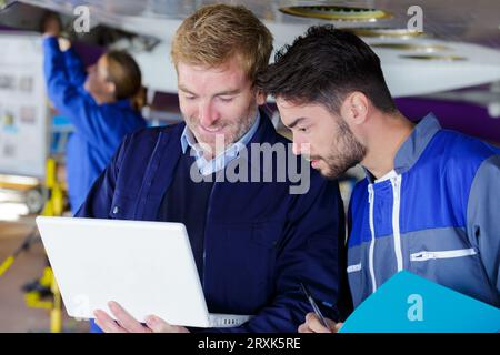 experienced mechanics using a laptop in repair shop Stock Photo