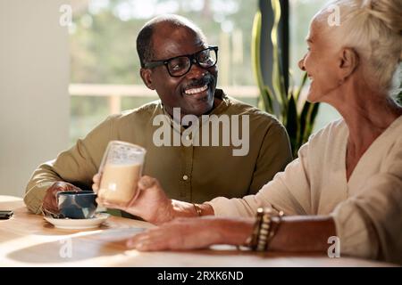 Happy senior couple sitting at table and talking to each other for cup of coffee in cafe Stock Photo