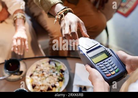 High angle view of customer paying for lunch with credit card while waiter holding terminal Stock Photo