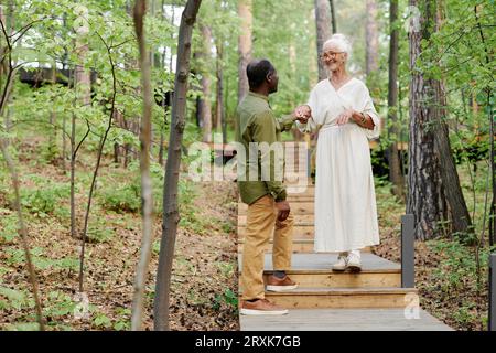 Multiethnic senior couple walking together in the forest in summer Stock Photo
