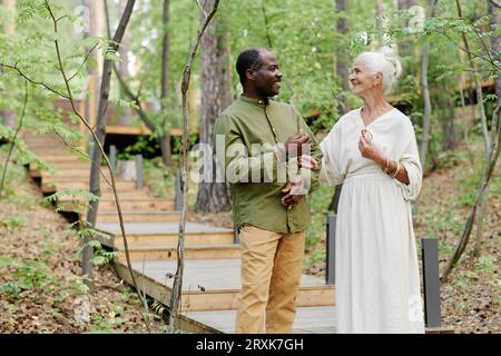 Senior couple enjoying their walk outdoors, they standing in the forest and talking to each other Stock Photo