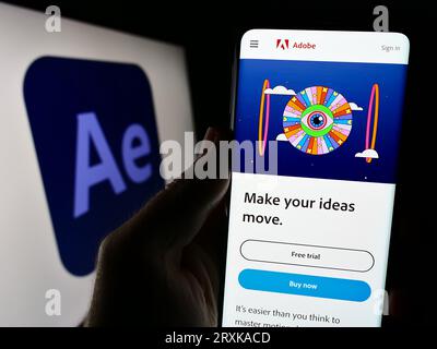 Person holding cellphone with website of motion graphics software Adobe After Effects on screen with logo. Focus on center of phone display. Stock Photo