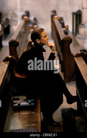 A young woman sits alone in empty church, she has come for quite contemplation. High Church of England, St John the Baptist church, Holland Park Road, Shepherd's Bush, London, England 1985 1980s UK HOMER SYKES Stock Photo