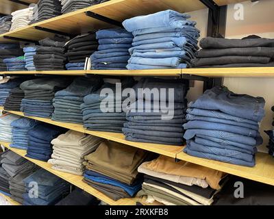 Many blue and black jeans in closet. Stack of jeans on shelf. Concept of buy, sell , shopping and denim fashion Stock Photo