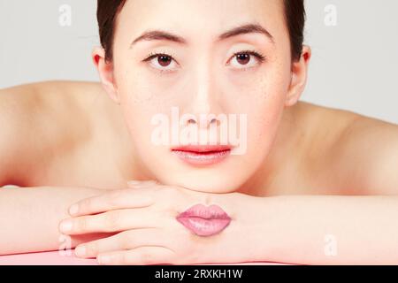 Young woman with lips drawn on her hand Stock Photo