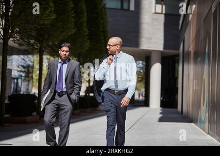 Businessmen walking along sidewalk together Stock Photo