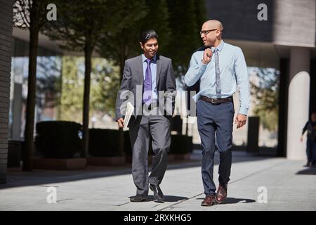 Businessmen walking along sidewalk together Stock Photo
