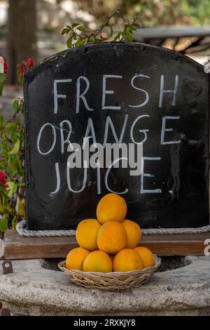 sighn advertising fresh orange juice with a bowl full of fresh oranges in the foreground, fresh fruit juices. Stock Photo