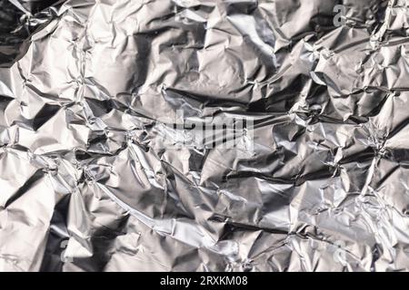 old used crumpled aluminum foil , close-up of a foil structure with crumbs from food Stock Photo